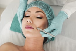 Dermaplaning along the jaw with a blade